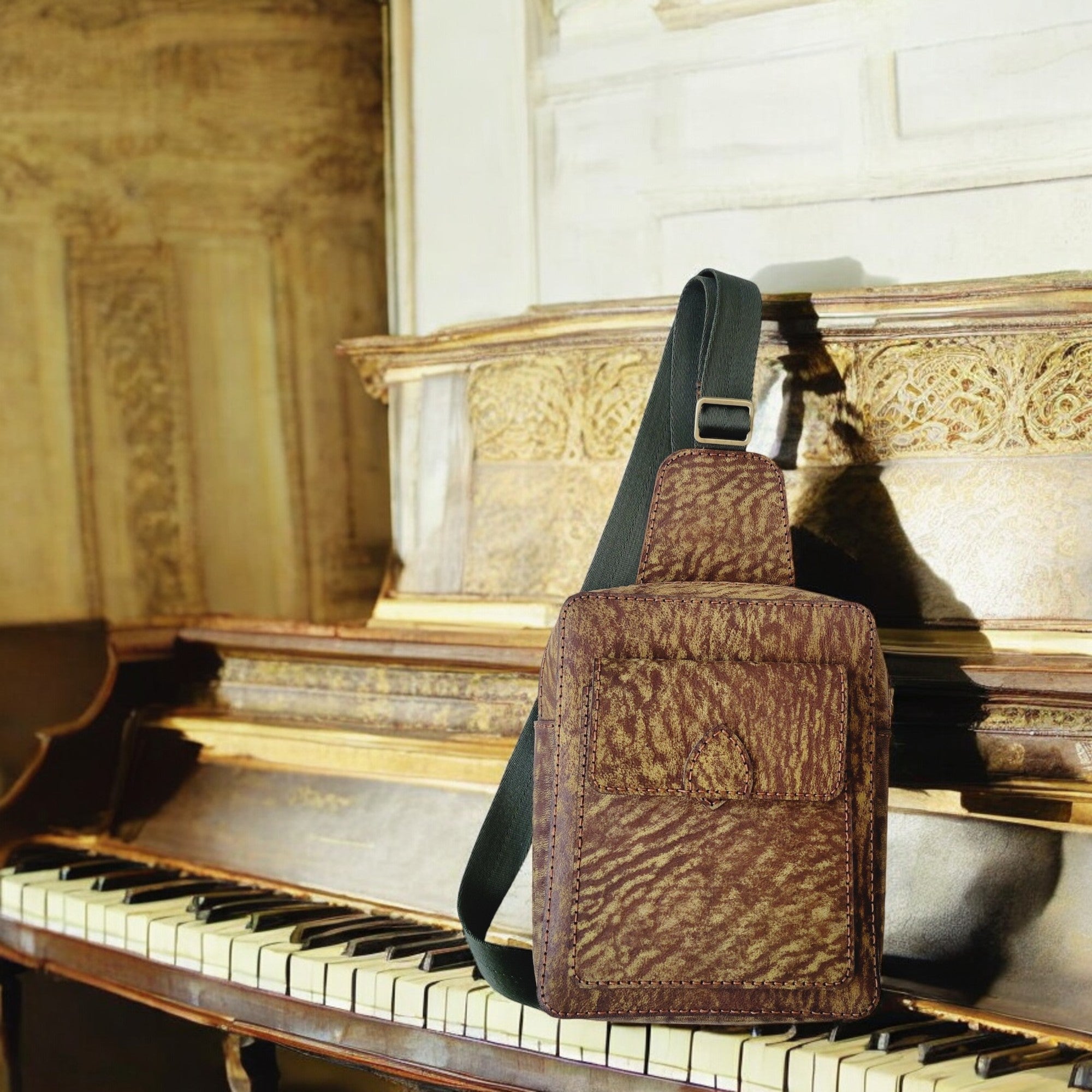 Compact camel-leather crossbody sling with large interior pocket, handcrafted in Canada.